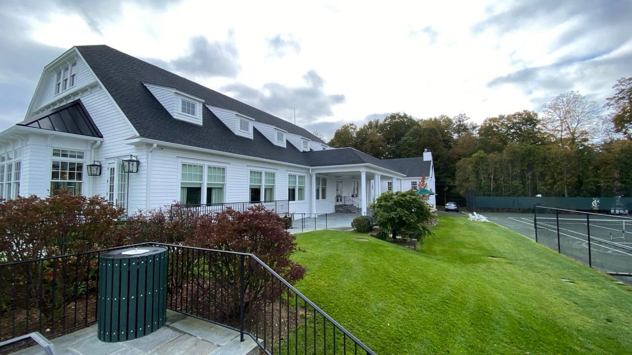 Gutter repair and inspection on large commercial clubhouse with gambrel roof and white clapboard siding — Westchester County