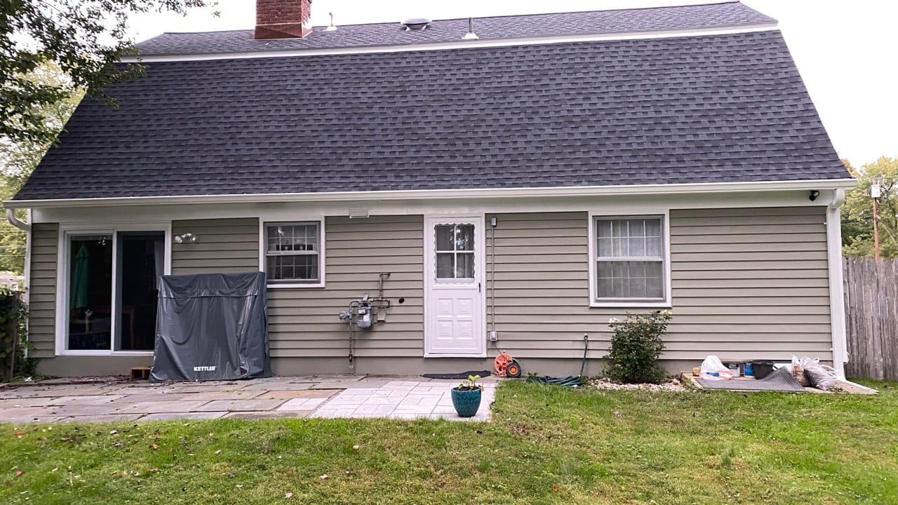 Ranch-style home with dark architectural shingles and white seamless gutters after repair — Connecticut