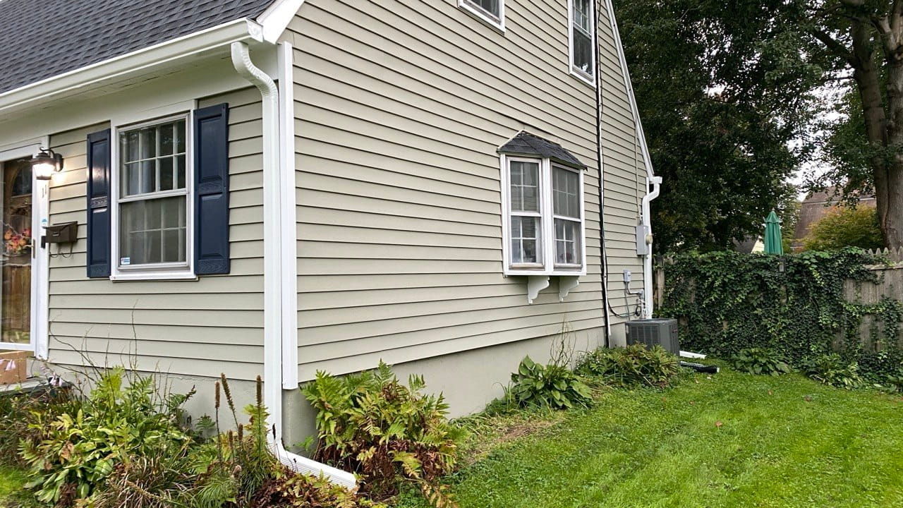 Gutter repair and downspout replacement on vinyl siding colonial with navy shutters — Westchester County NY