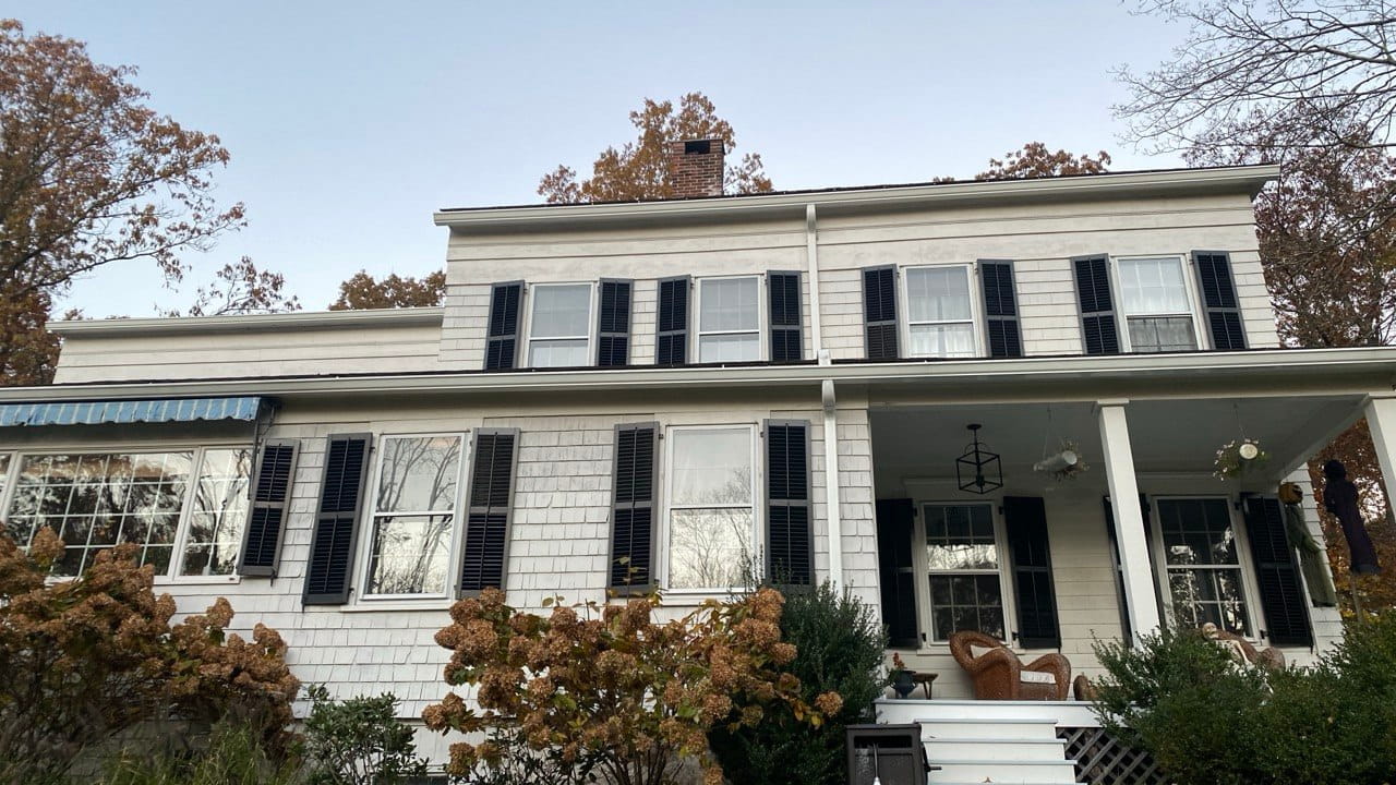 White colonial cedar shingle home with new seamless gutters and black shutters — Westchester County gutter repair